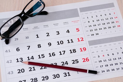 Black glasses and a pencil lie on the calendar